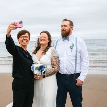 Bride and groom and Justice of the Peace standing on a beach taking a selfie photo.