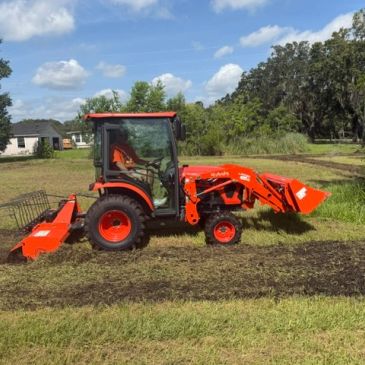 Orange tractor on grass field under blue sky.