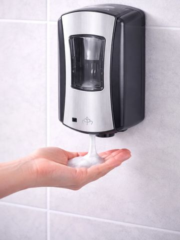 Wall-mounted unit with hand underneath and sanitizer dispensing.
