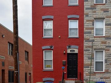 Red brick townhouse with black door and windows.