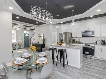 Modern kitchen and dining area with white cabinetry and gray floors.