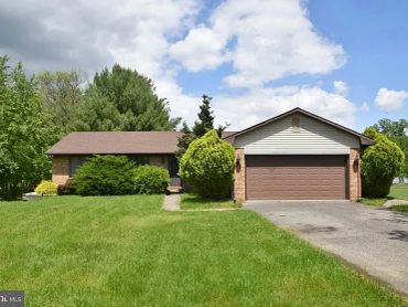 Suburban brick house with a green lawn and driveway.