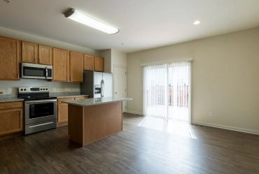 Empty kitchen with island and sliding glass door.