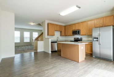 Spacious kitchen with wooden cabinets and stainless steel appliances.