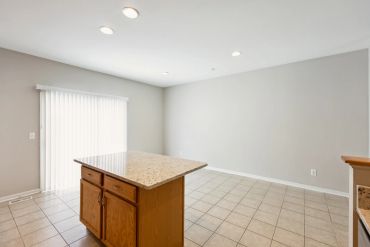 Empty kitchen with island and tiled floor.