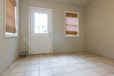 Empty room with tile floor and windows with shades.