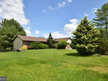 House with a spacious green lawn and trees.