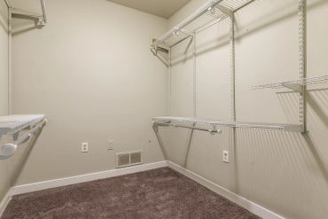 Empty walk-in closet with wire shelves and carpeted floor.