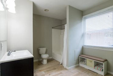 Modern bathroom with toilet, bathtub, and bench.