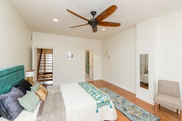 Bright modern bedroom with wooden floor and ceiling fan.