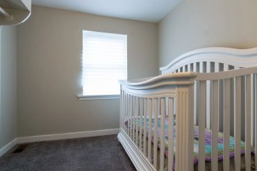 Empty baby crib in a minimally furnished room.
