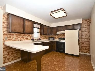 Vintage kitchen with wooden cabinets and patterned walls.