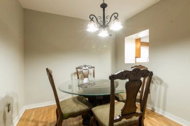 Dining area with glass table and classic chairs.