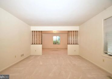 Empty beige living room with a window and divider.