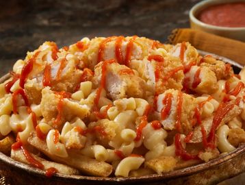 Fried chicken bites on mac and cheese fries drizzled with hot sauce.