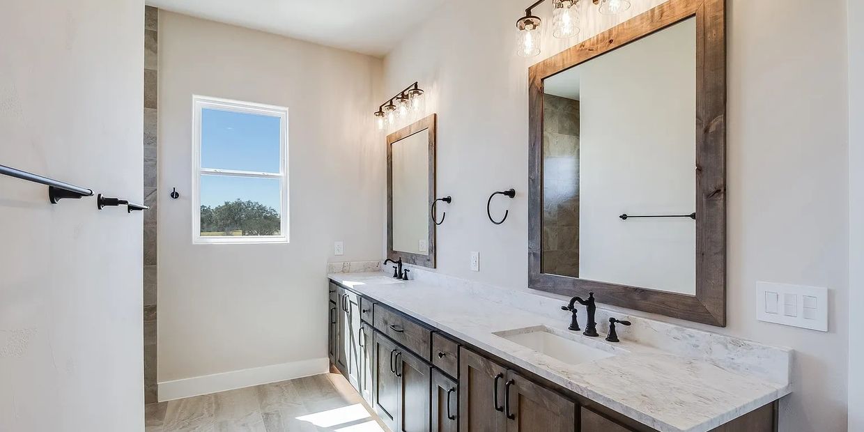 Modern bathroom with double sinks and wooden cabinetry.