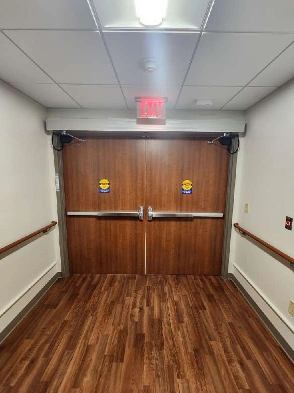 Wooden double exit doors in a hallway.