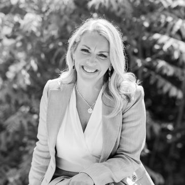 Woman in a business suit sitting outside and smiling