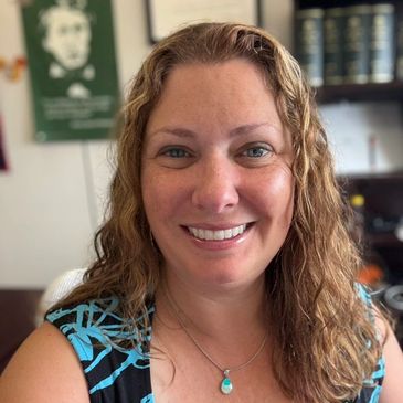 Woman standing indoors smiling at the camera.