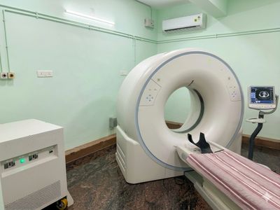 A CT scan machine in a medical room with a patient table.