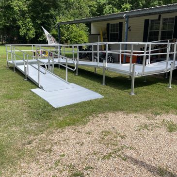 Metal wheelchair ramp and deck outside a yellow house.