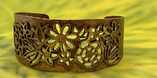 Intricately designed brass cuff bracelet with floral cut-out patterns.