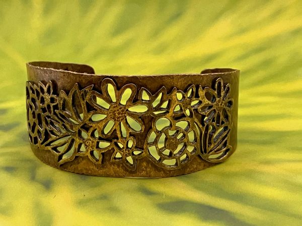 floral bronze and brass cuff on a light green background