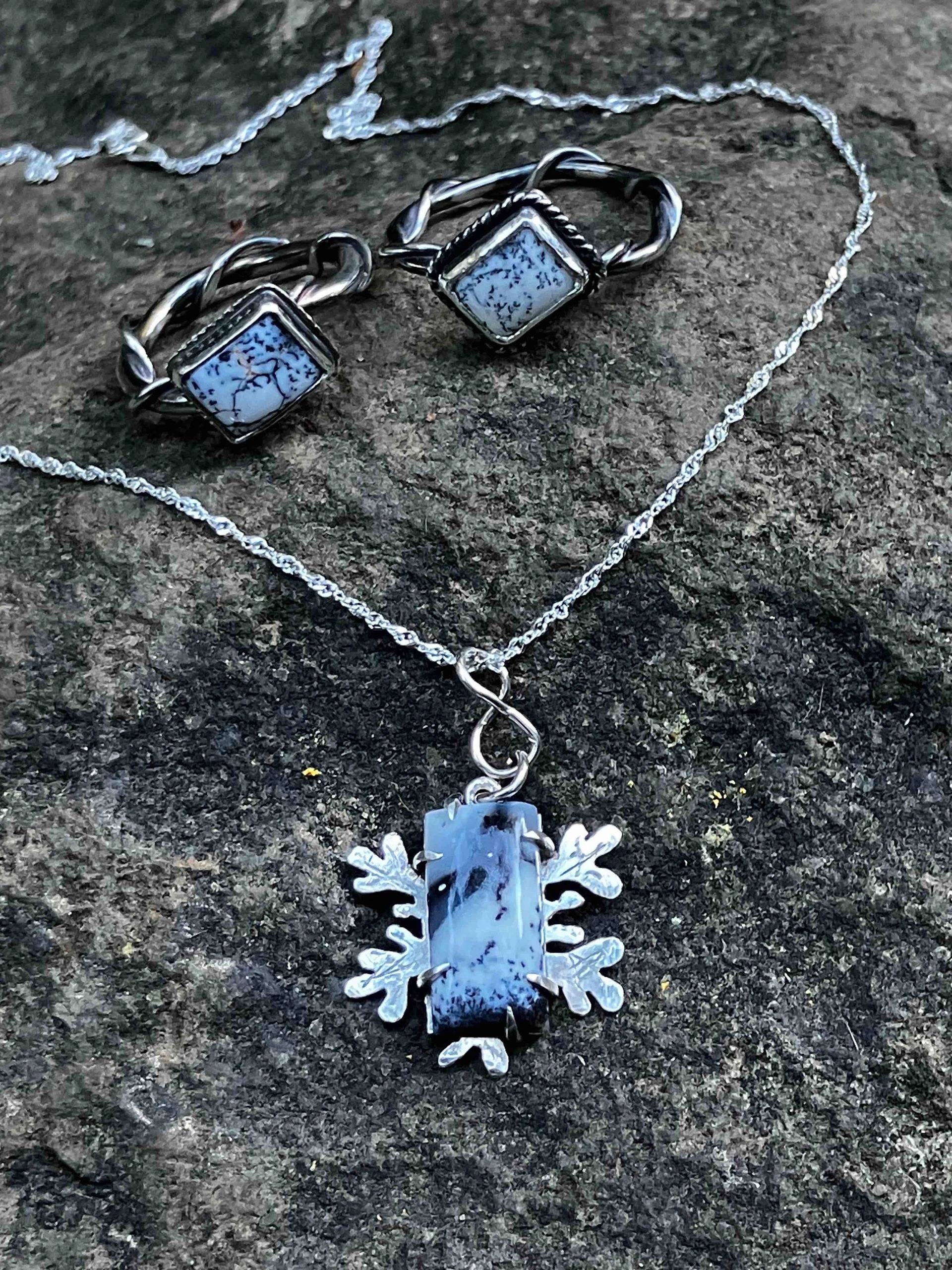 Silver jewelry with blue stone accents on a rock.