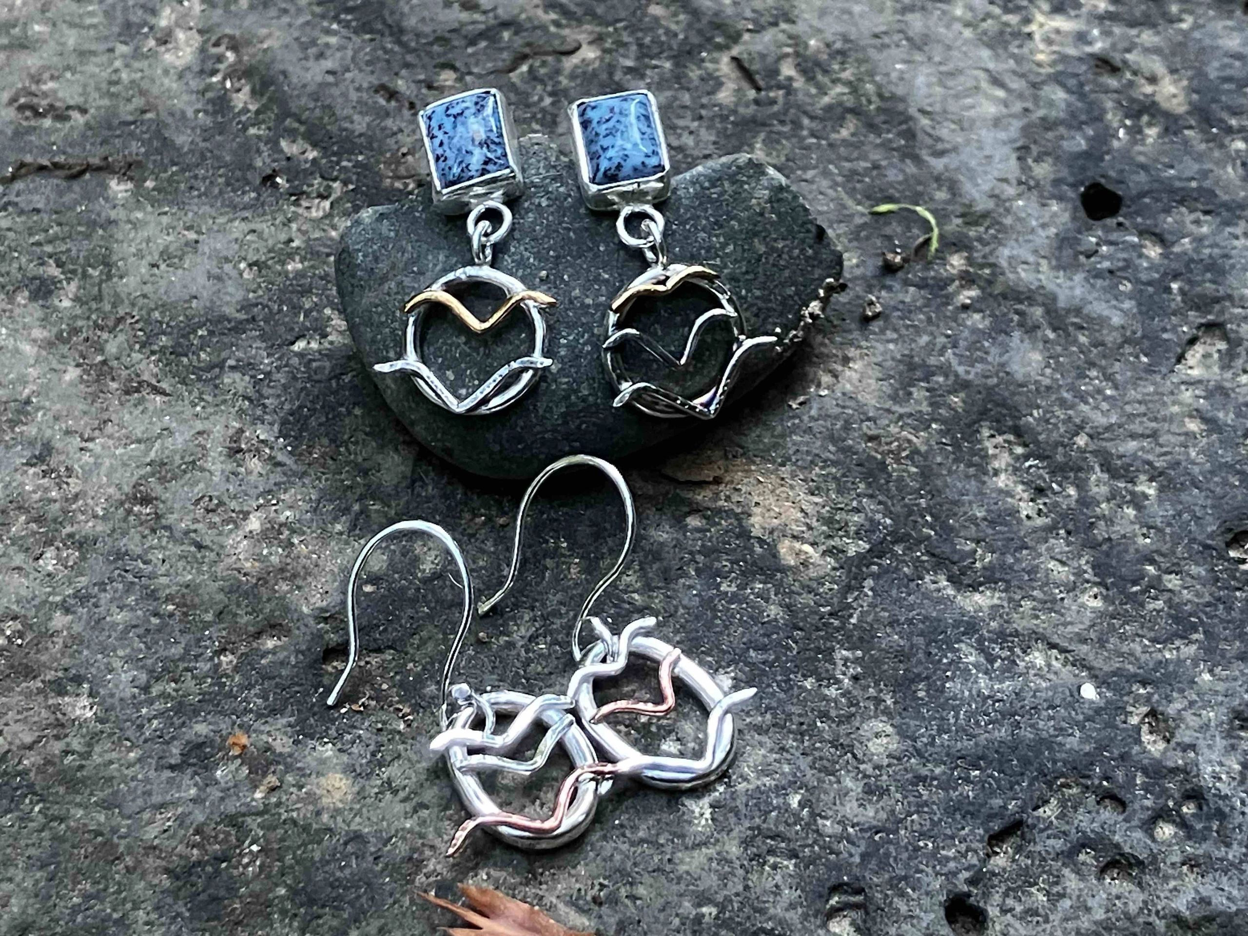 Two pairs of unique handmade earrings on a stone surface