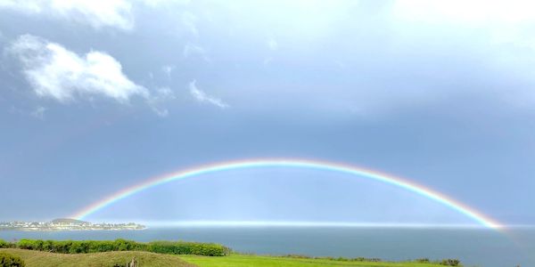 A full rainbow looking east of Oak Harbor towards the Cascade Range in Washington State.