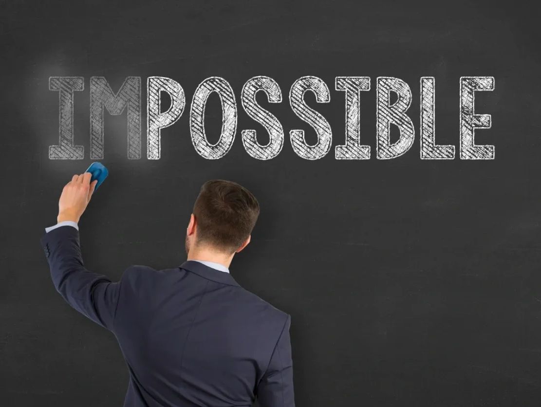 Man with the word Impossible hanging from a blackboard