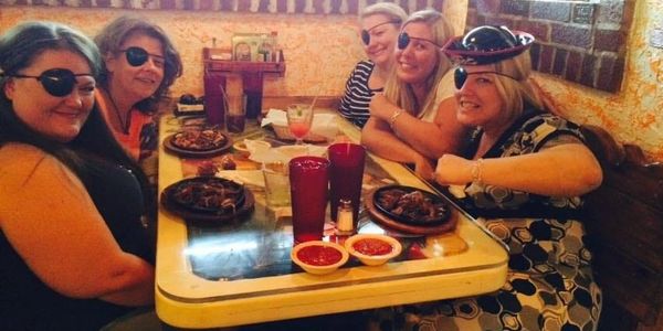 Five women with eye patches enjoying a meal together at a restaurant.