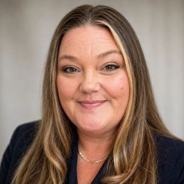Smiling woman with long hair and a gold chain necklace.