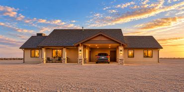 Sunset view of a house with a car parked under the porch.