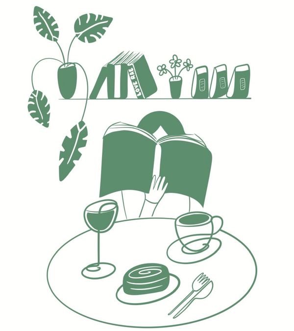 A person reads a book with coffee, dessert, and wine on the table, surrounded by plants and books.