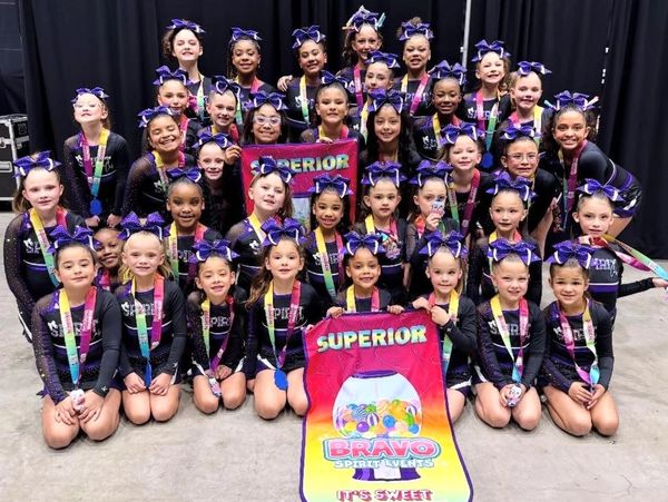 Youth cheerleading team posing with medals and banners.
