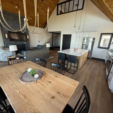 Modern open-concept kitchen and living area with wood accents and black furniture.