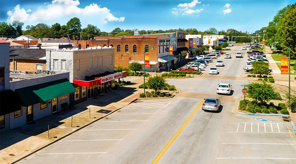 Small town main street with a historic theater and parked cars.