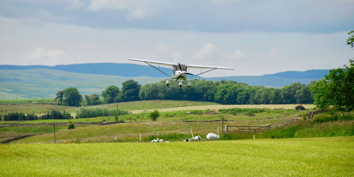Microlight Aircraft over field coming in to land. 