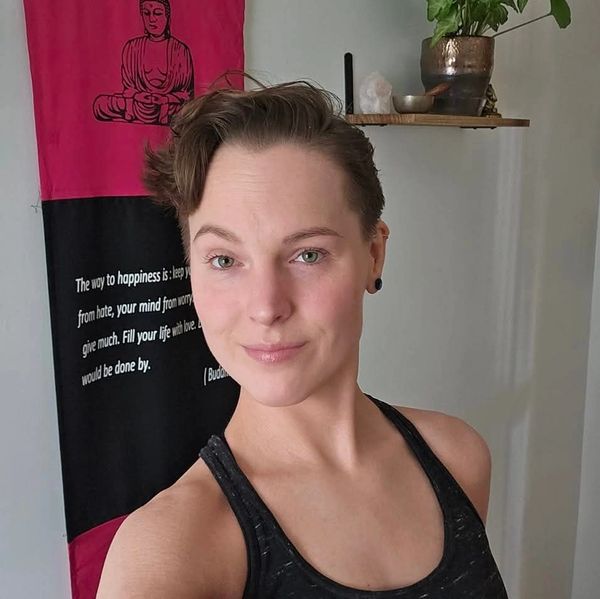Person taking a selfie in front of a Buddha-themed wall hanging.