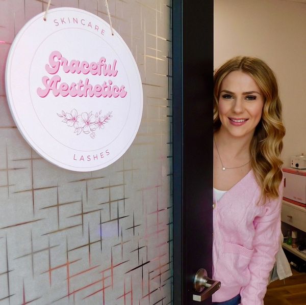 Woman smiling and standing at the door of Graceful Aesthetics salon.