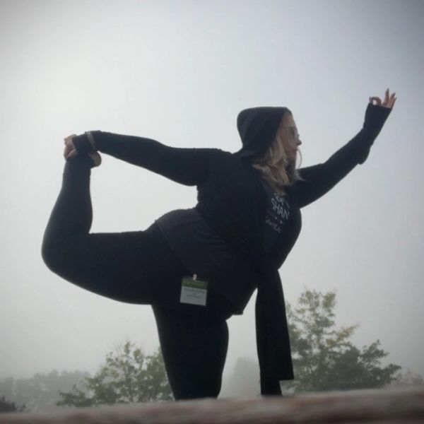 Person practicing yoga outdoors in foggy weather.