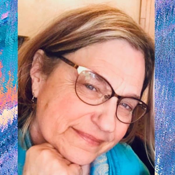 Close-up of a smiling woman wearing glasses and a blue scarf.