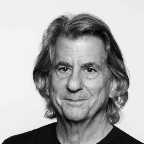 Black and white portrait of an older man with long hair and a subtle smile.
