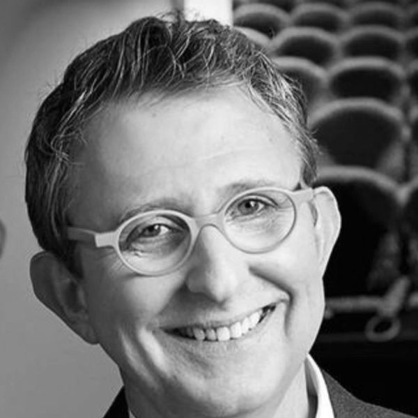 Smiling man with glasses in a black-and-white photo.
