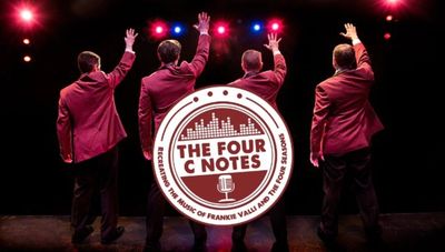 Four men in maroon jackets wave on stage under colorful lights.