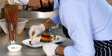 Chef carefully plating a gourmet dish in a professional kitchen.