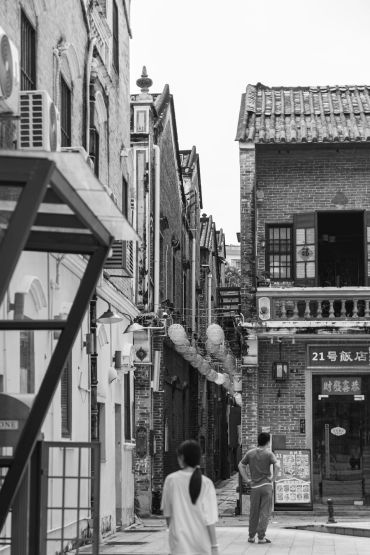 Black and white street scene with traditional buildings and pedestrians.
