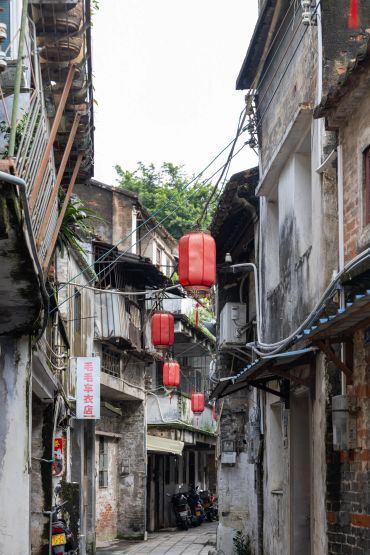 Narrow alley with old buildings and red lanterns.