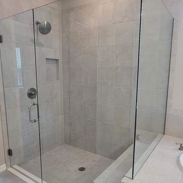 Spotless and shiny glass door around a tile shower with fresh clean grout lines.